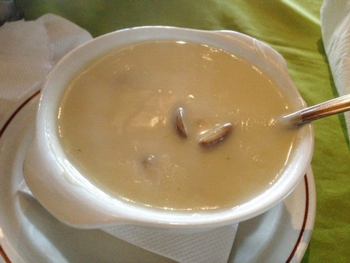 Plato hondo de crema de guacucos con cubos de papa y pan tostado al lado