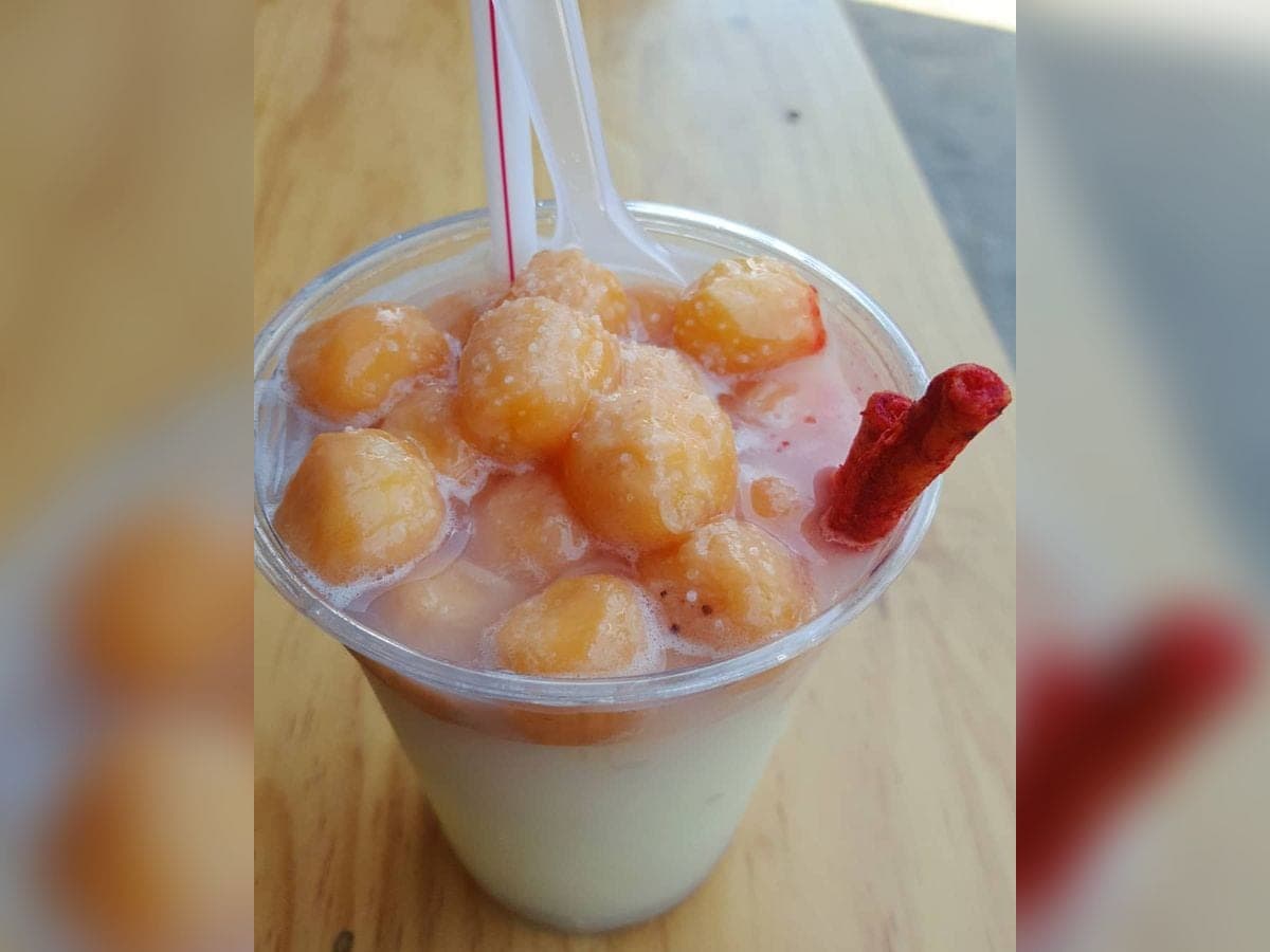 Mamonada caroreña servida en vaso grande, cremosa y con las semillas de mamón