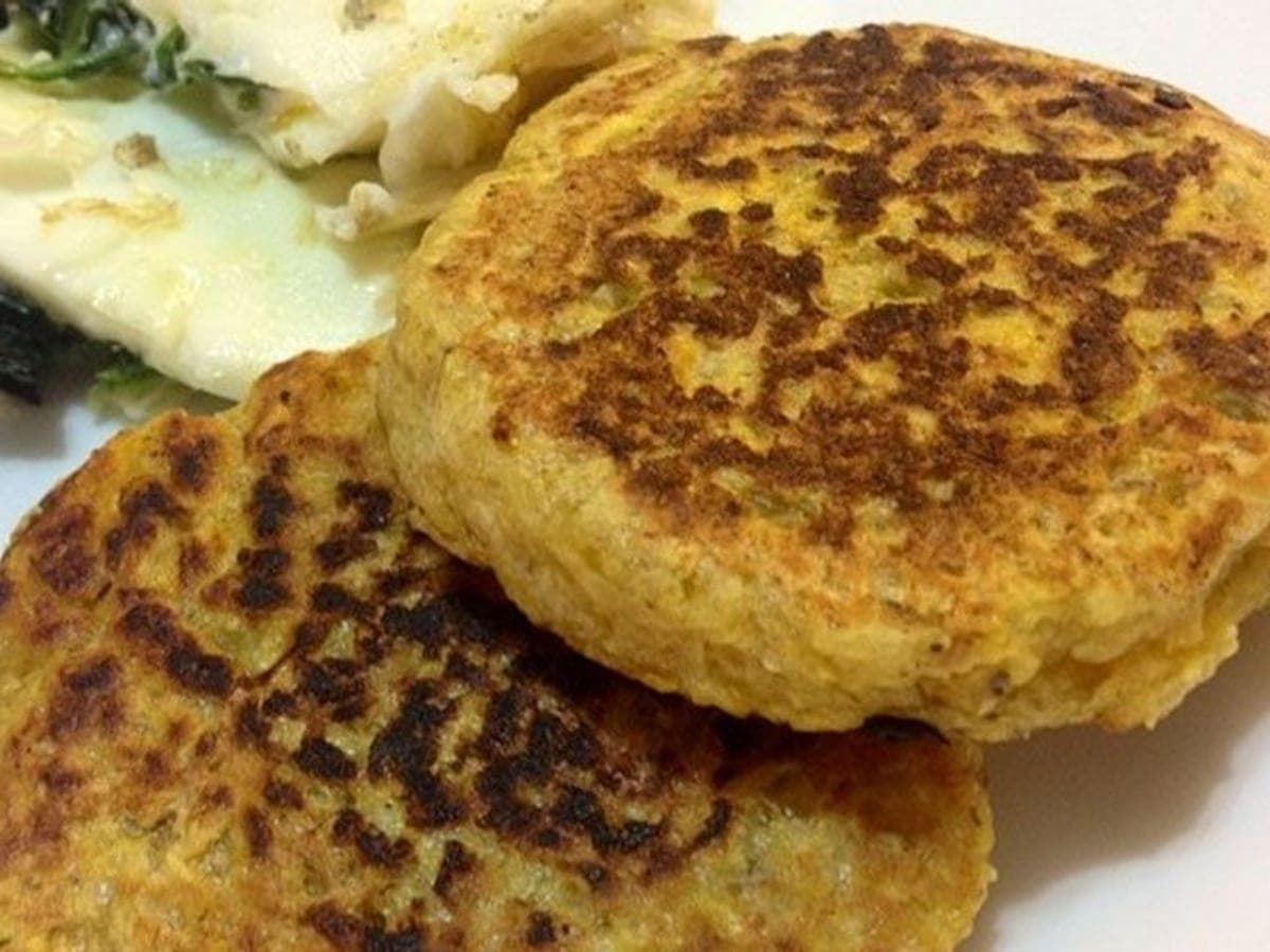 Arepas de plátano verde doradas en la plancha, abiertas y rellenas