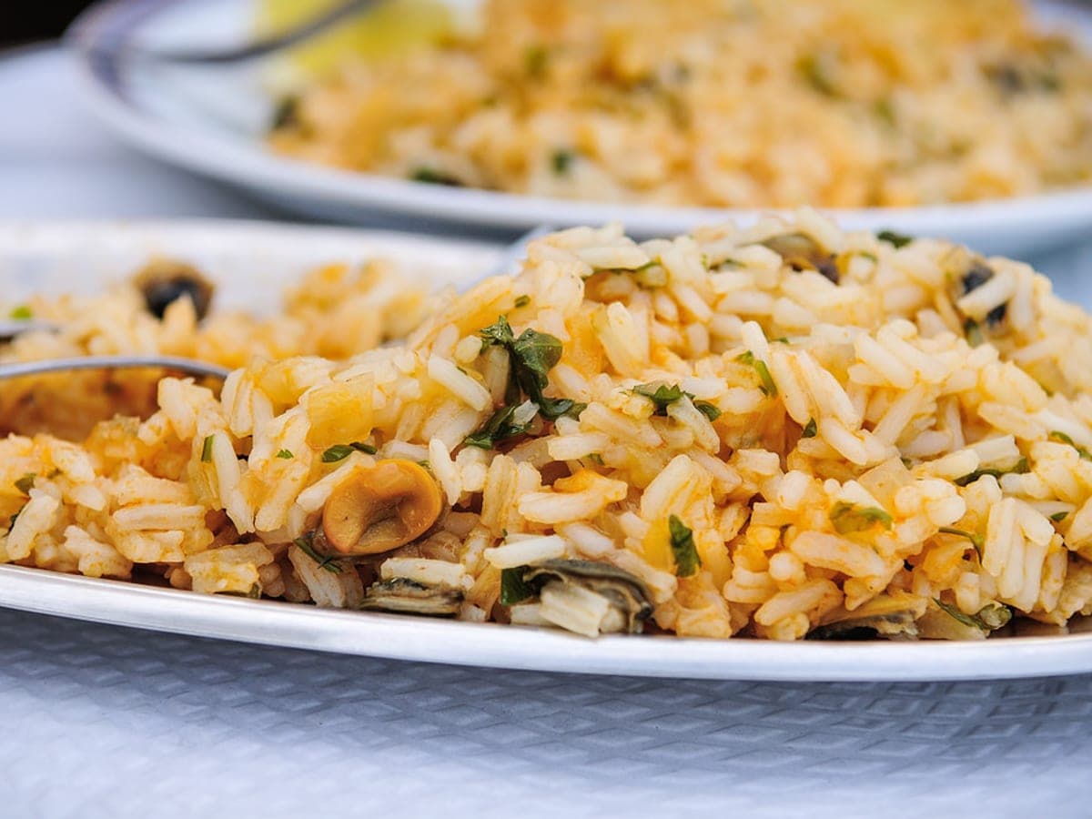 Arroz con lapas de mar servido en una olla, con cilantro picado por encima