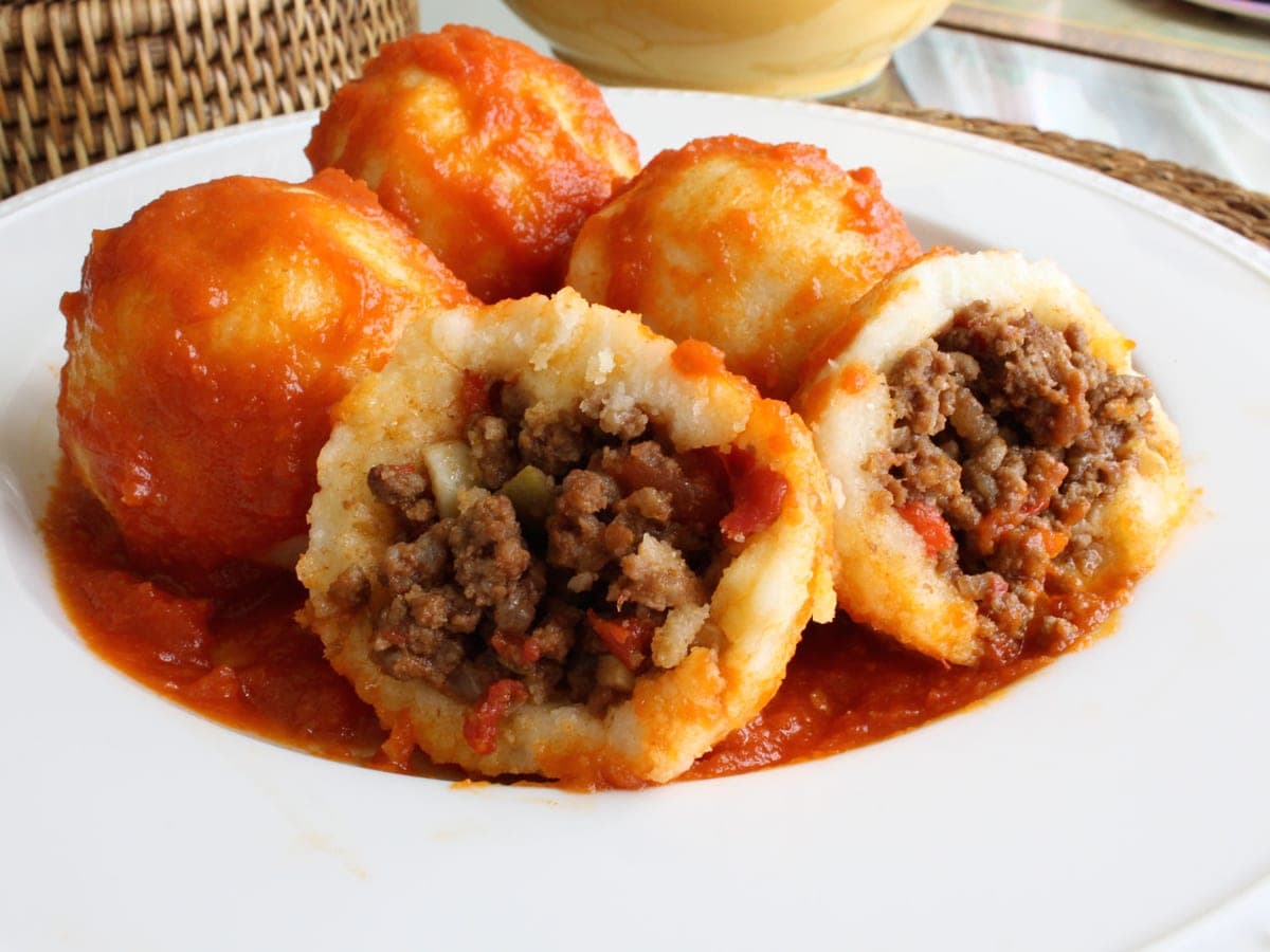 Bollos pelones zulianos bañados en salsa de tomate casera, servidos en un plato