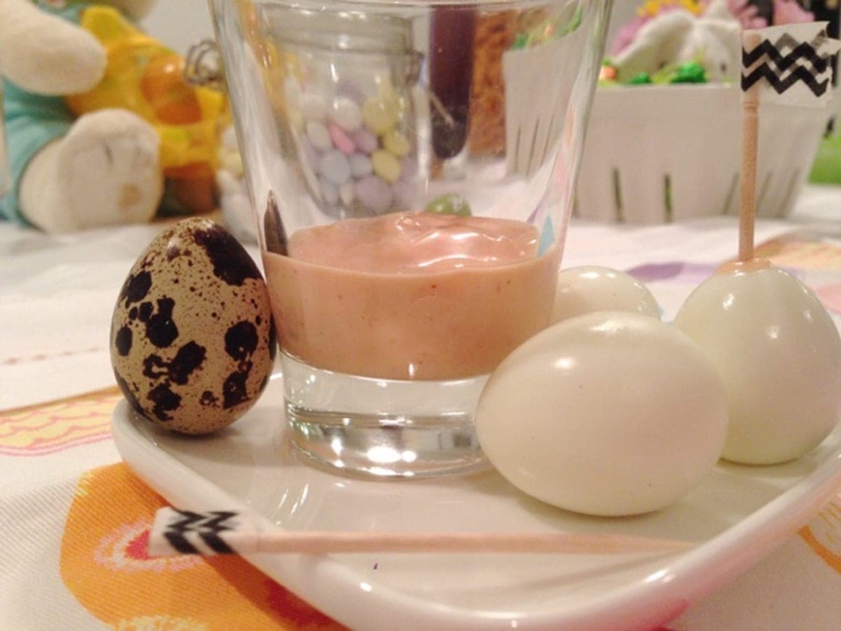Huevos de codorniz pelados servidos junto a un cuenco de salsa rosada