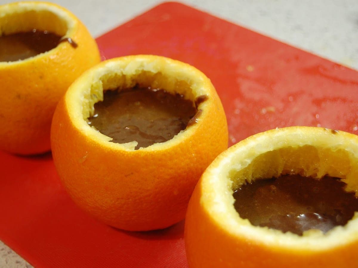 Mitades de naranja rellenas de crema y espolvoreadas con chocolate negro rallado