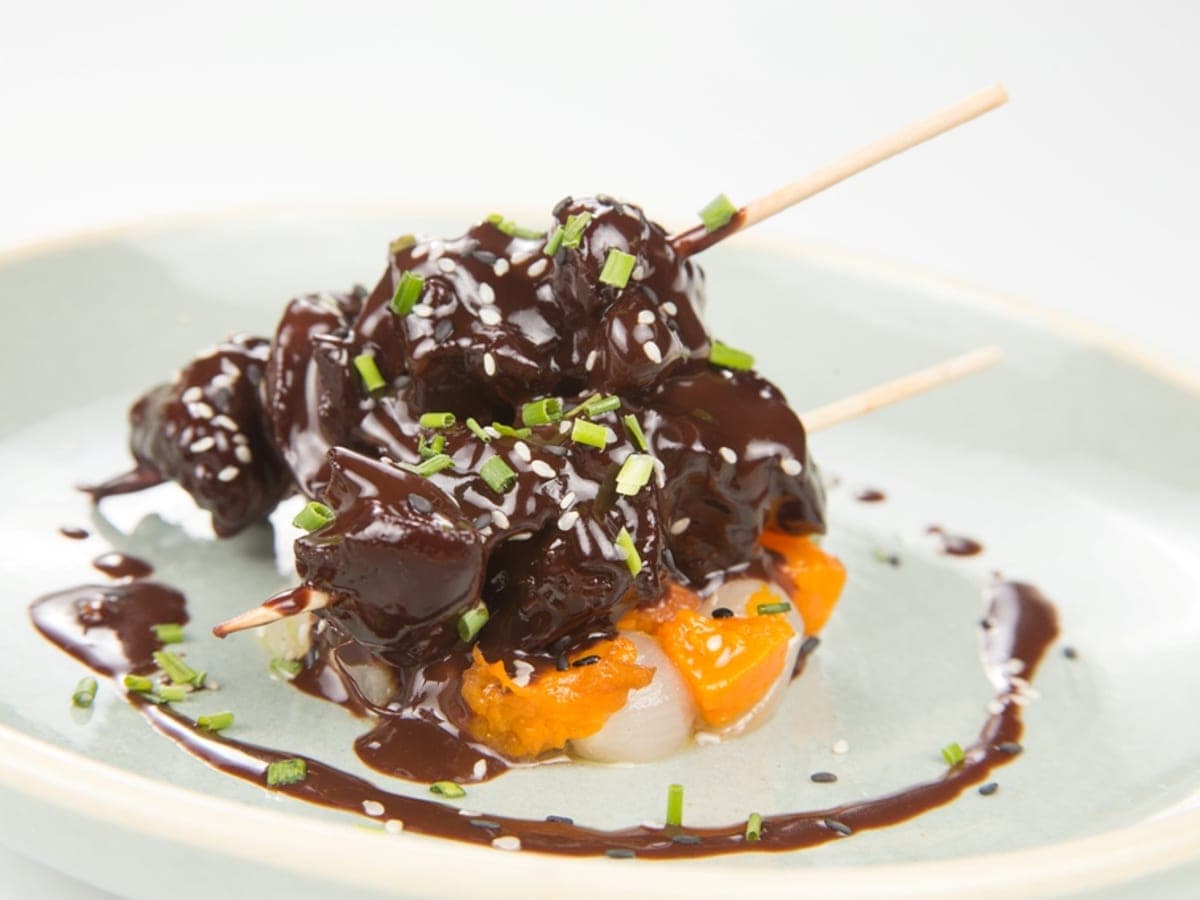 Pechuga de pollo dorada bañada en salsa de cacao, con chalotas en juliana