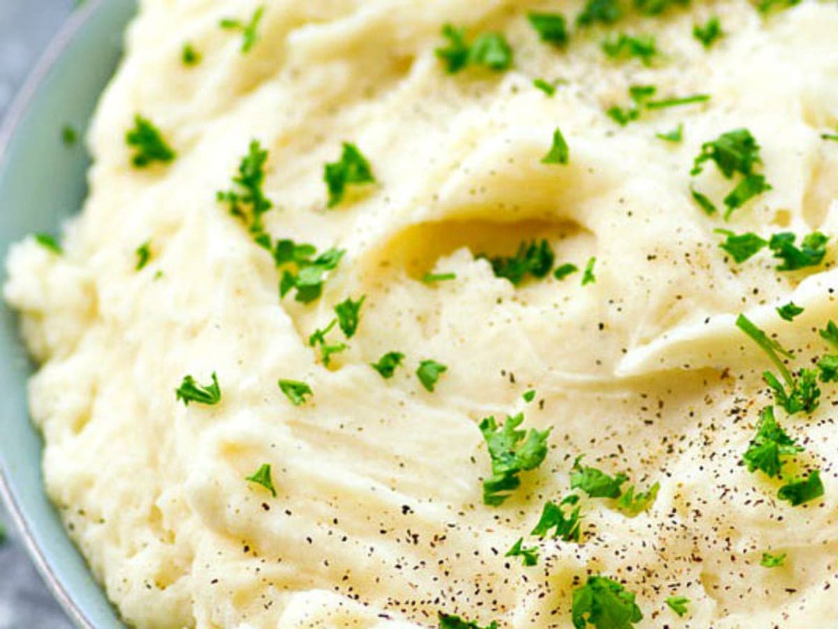Bol de puré de papas cremoso con perejil picado y aceite de oliva por encima
