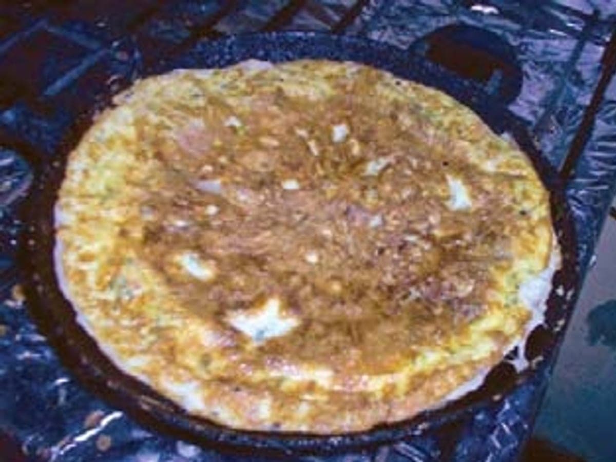 Tortilla de huevos dorada servida en un plato con arepa al lado