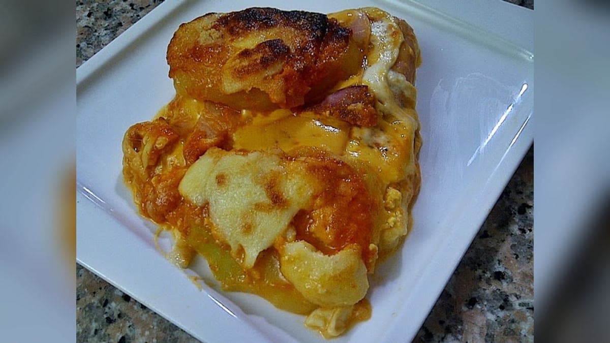 Porción de turmada paramera con capas de papa, jamón y quesos gratinados