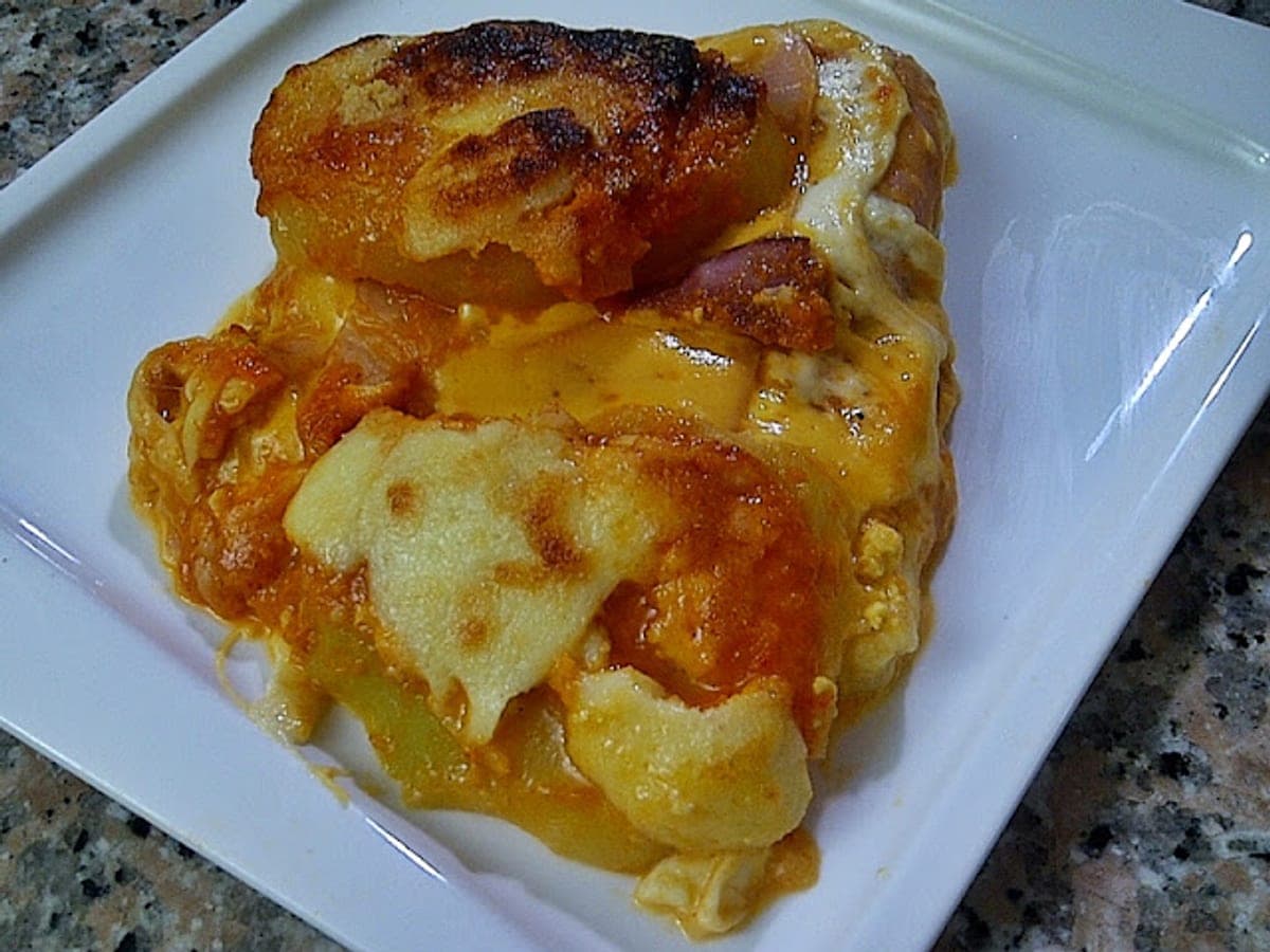 Porción de turmada paramera con capas de papa, jamón y quesos gratinados